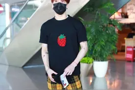王嘉尔现身机场，穿搭黑色因草莓印花T，搭配法兰绒格子长裤图片