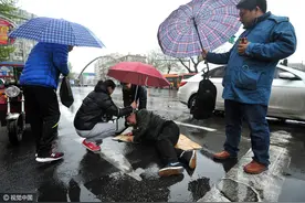 青岛：老人雨天摔倒路口，众人撑伞垫纸箱叫救护车图片