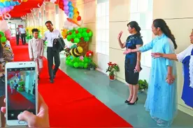 学生着礼服 牵手父母跨“毕业门”图片