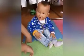 萌宝宝坐在地上自己给自己玩的非常嗨皮图片