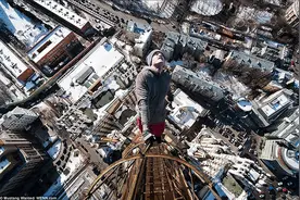 用指尖将身体悬挂在几百英尺高的大楼上的男子图片