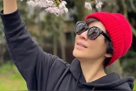 55岁刘嘉玲素颜赏樱，穿卡通卫衣配健美裤，戴红帽拍游客嗅花照图片