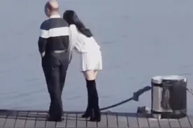 广东深圳，一位秃头大叔和一妙龄女子散步海边，女子时而撒娇卖萌图片