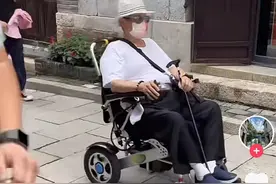 69岁洪金宝坐轮椅游山东古镇，众人陪同排场大，小13岁妻子相伴图片