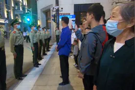 拥挤人潮里，奶奶终于看到对面“人墙”中认真执勤的孙子，想拍照片却激动得打不开相机……图片