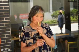 7旬大妈做手工卖钱，中午啃个桃子当午饭，游客搞完价却少给5块钱图片