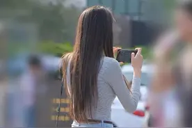 高挑美女一身时尚在街上，拿起手机拍照自信十足图片