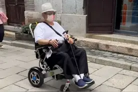 69岁洪金宝坐轮椅逛古镇，众人陪同排场大，混血小娇妻状态气质佳图片