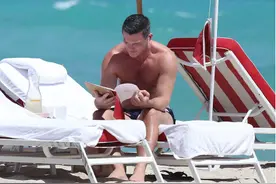 卢克·伊万斯露发达肌肉秀健硕身材，坐海边看书画风奇特图片