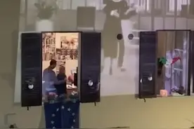 居家隔离的意大利夫妇在窗前跳舞，邻居投影经典电影定格浪漫瞬间图片