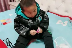 宝宝坐在床上拿着小剪刀，耐心的剪，放在床上的剪纸视频封面