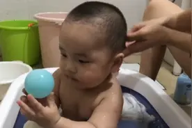 爱洗澡澡的小宝宝坐着凳子上玩球球，还戴了洗头帽子洗头。视频封面