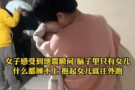 女子感受到地震瞬间，穿着薄薄的外套，光着脚抱起女儿就往外跑。图片