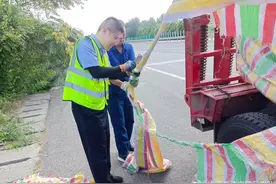 晋城往太原方向一重型平板半挂车装载设备所苫盖的彩条篷布拖在路上，且有部分篷布已缠绕在挂车车轮里..图片