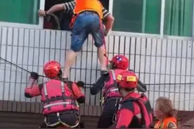消防员以肩作梯，无数次蹲起中转移受困者，大声安慰：“别怕！踩我肩膀！”图片