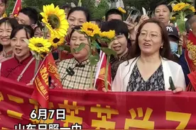 6月7日早上7点多，日照一中东校送考家长们来了。他们都手拿葵花祝愿考生们一举夺魁，一些考生家长还身着旗袍，祝愿考生能旗开得胜！（刘涛 郑玥 日照报道图片