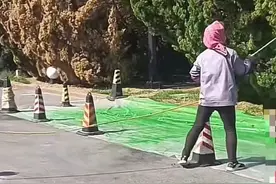 大连一工人给树木喷洒绿色液体，物业：是一种肥料，减少植物水分流失图片