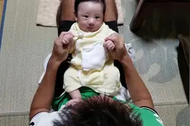 宝宝躺在爸爸的大腿上,被爸爸拉着小手做运动,一脸不情愿的表情视频封面